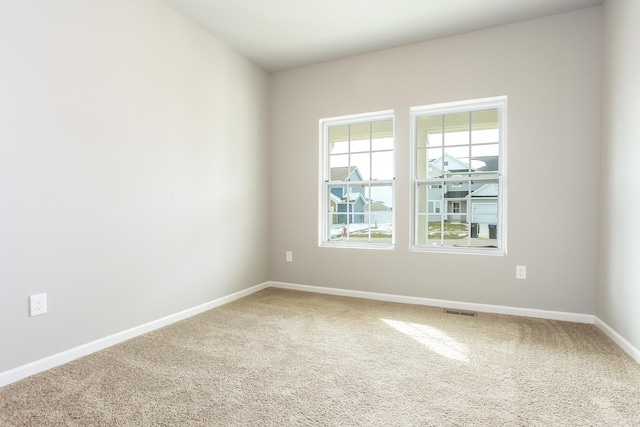 unfurnished room featuring carpet, visible vents, and baseboards