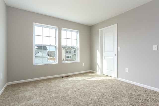 spare room with light carpet, baseboards, and visible vents