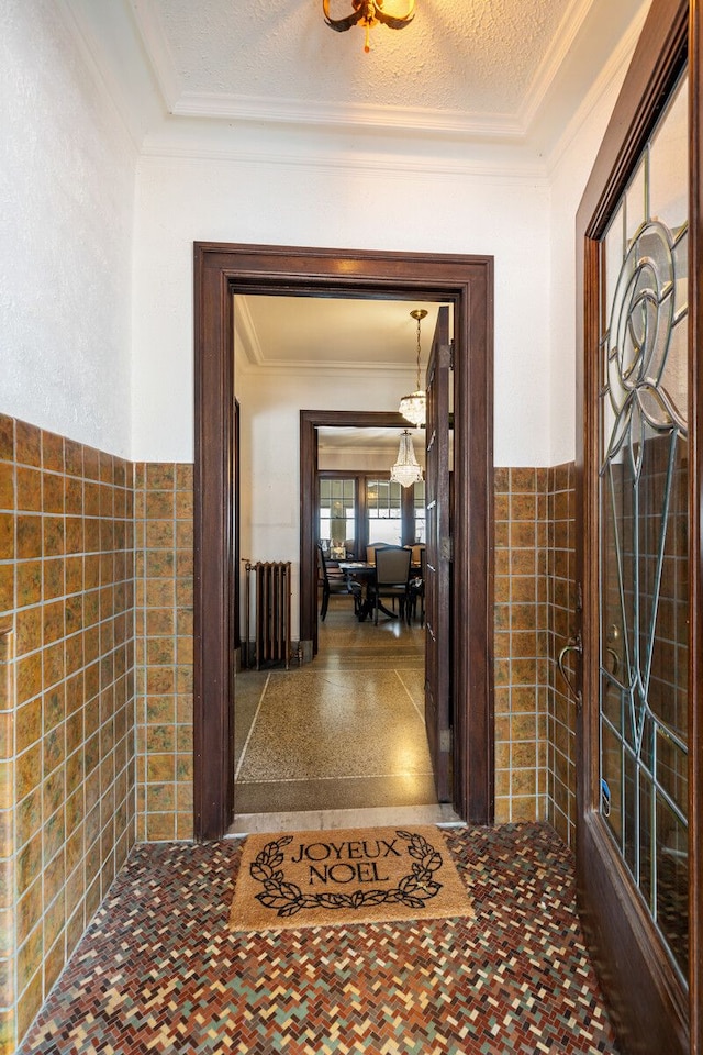 hall with tile walls and ornamental molding