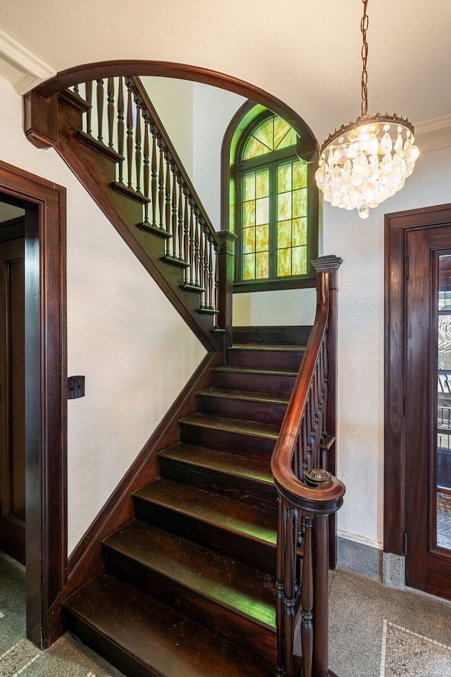 staircase with ornamental molding and a notable chandelier