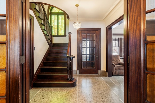 foyer entrance with an inviting chandelier and crown molding