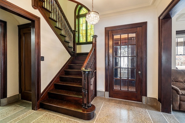 entryway with crown molding and a notable chandelier