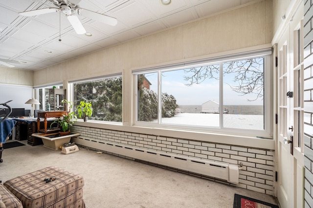 sunroom featuring a water view, baseboard heating, and ceiling fan