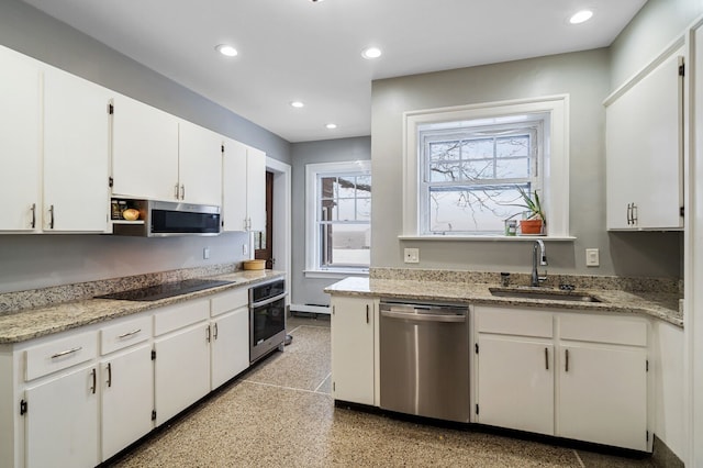 kitchen with light stone counters, stainless steel appliances, white cabinetry, and sink