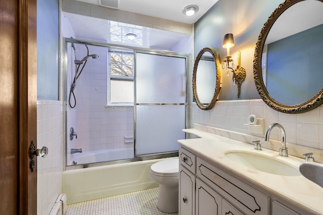 full bathroom featuring bath / shower combo with glass door, a baseboard radiator, tile walls, tile patterned flooring, and toilet