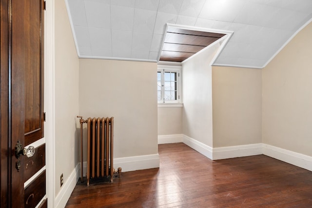 bonus room with radiator heating unit, dark wood-type flooring, and vaulted ceiling