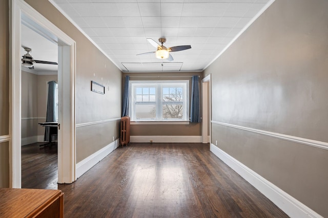 empty room with ceiling fan, dark hardwood / wood-style floors, ornamental molding, and radiator