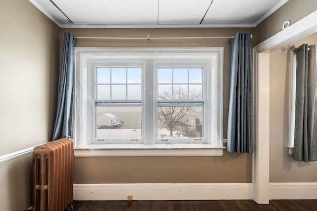 interior details with a drop ceiling, hardwood / wood-style flooring, radiator, and crown molding