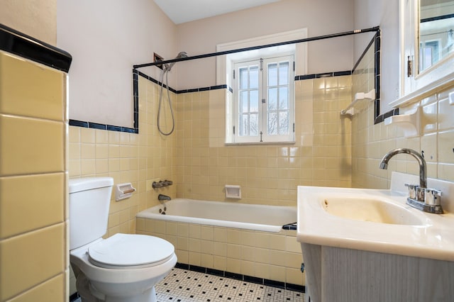 full bathroom featuring tile patterned flooring, toilet, vanity, tile walls, and tiled shower / bath