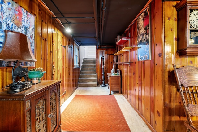 hallway featuring light colored carpet and wooden walls