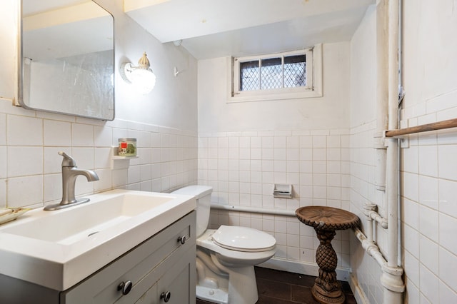 bathroom featuring vanity, toilet, and tile walls