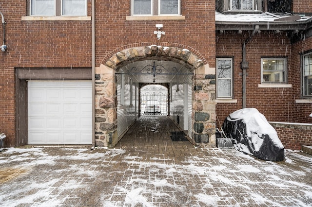 snow covered property entrance featuring a garage