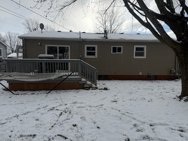 snow covered back of property with a deck