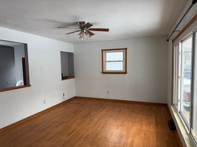 spare room with hardwood / wood-style flooring, ceiling fan, a textured ceiling, and a wealth of natural light