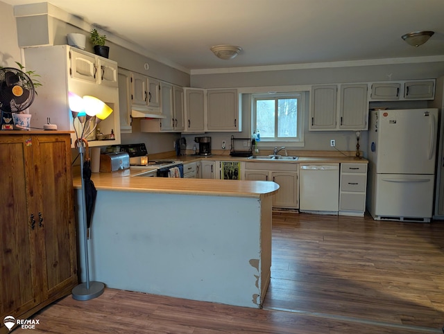 kitchen featuring sink, dark hardwood / wood-style flooring, kitchen peninsula, crown molding, and white appliances