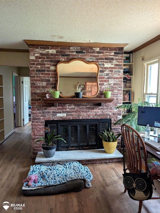 living room with a textured ceiling, ornamental molding, a fireplace, and dark wood-type flooring