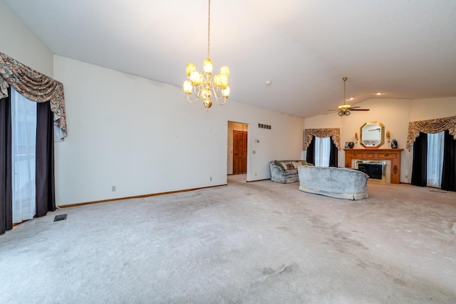 unfurnished living room featuring carpet flooring, ceiling fan with notable chandelier, and vaulted ceiling