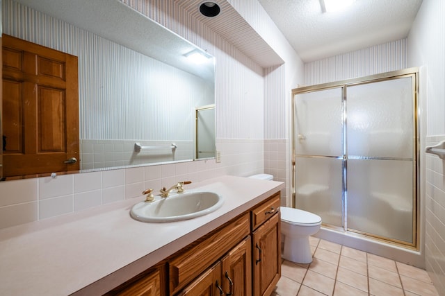 bathroom featuring tile patterned floors, an enclosed shower, tile walls, and a textured ceiling