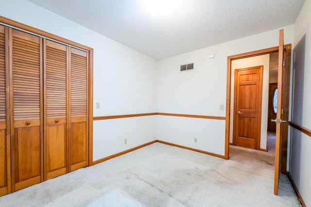 unfurnished bedroom featuring a closet, light colored carpet, and a textured ceiling