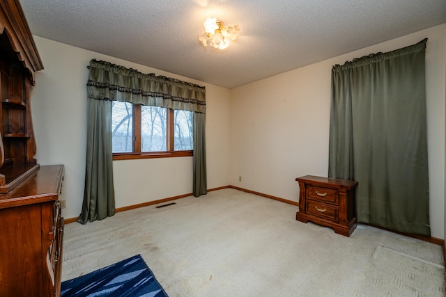 bedroom with a textured ceiling and light colored carpet