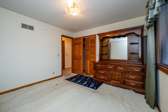 unfurnished bedroom with light carpet, a textured ceiling, and a closet