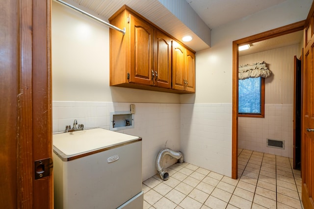 clothes washing area featuring washer hookup, cabinets, light tile patterned floors, and tile walls