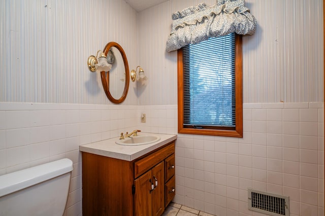 bathroom with tile patterned floors, vanity, tile walls, and toilet