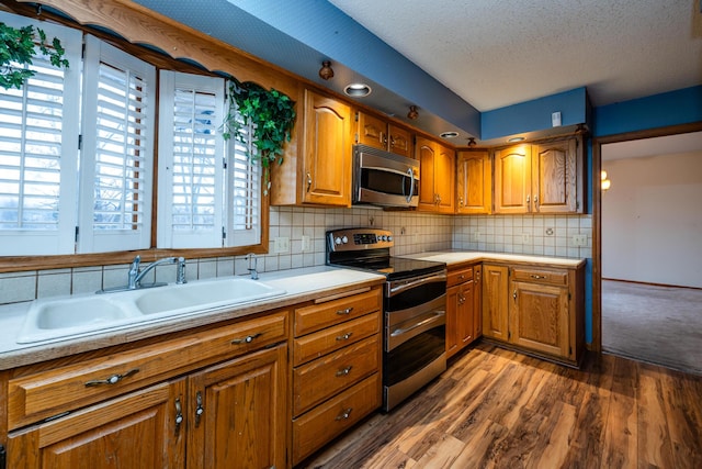 kitchen with tasteful backsplash, a textured ceiling, stainless steel appliances, sink, and dark hardwood / wood-style floors