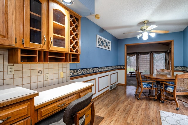 interior space with backsplash, ceiling fan, light hardwood / wood-style floors, and a textured ceiling