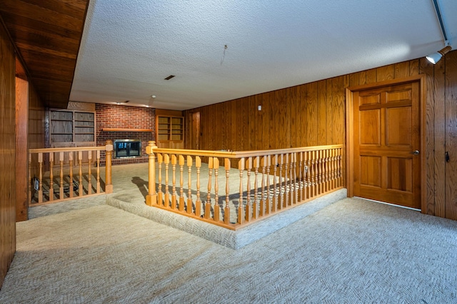 interior space with carpet, a textured ceiling, and wood walls