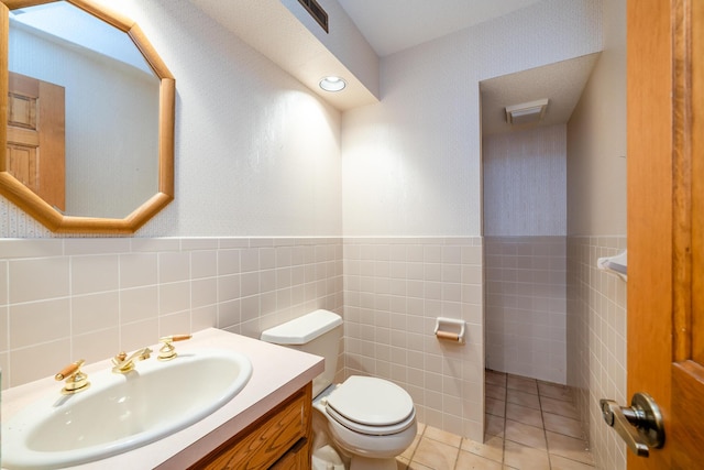 bathroom featuring tile patterned flooring, vanity, toilet, and tile walls