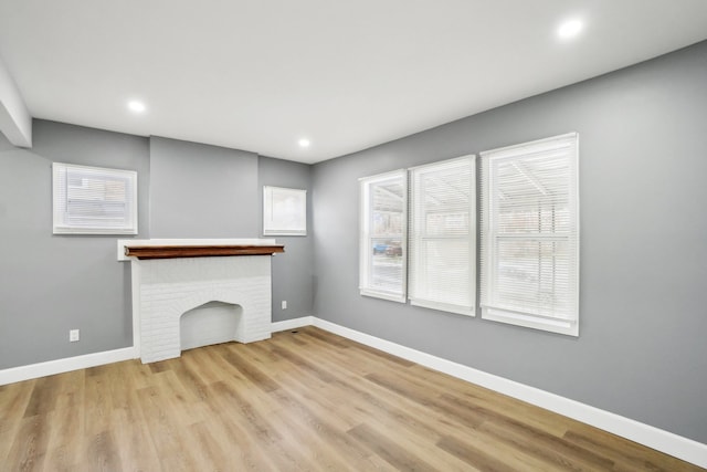 unfurnished living room featuring a brick fireplace and light hardwood / wood-style flooring