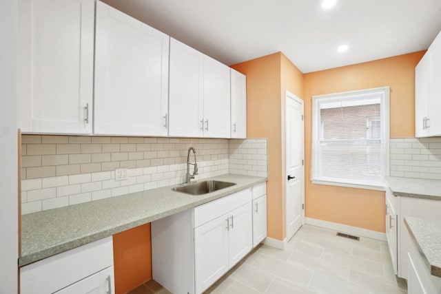 kitchen with backsplash, sink, white cabinets, and light tile patterned floors