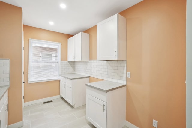 kitchen with backsplash, white cabinets, and light tile patterned flooring