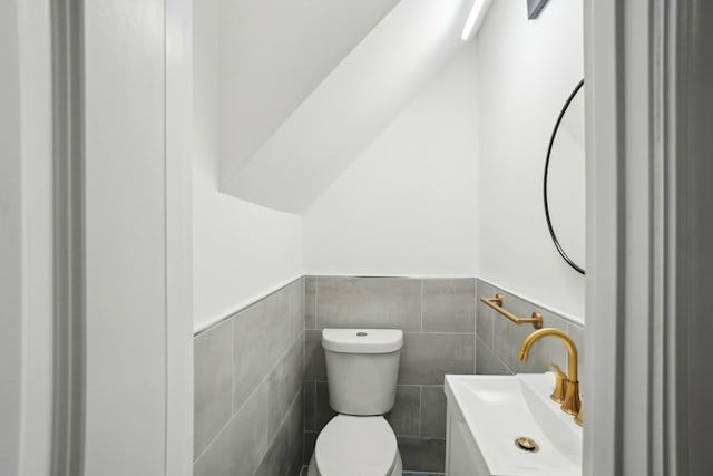 bathroom featuring vanity, toilet, and tile walls