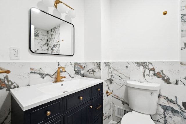 bathroom featuring vanity, toilet, and tile walls