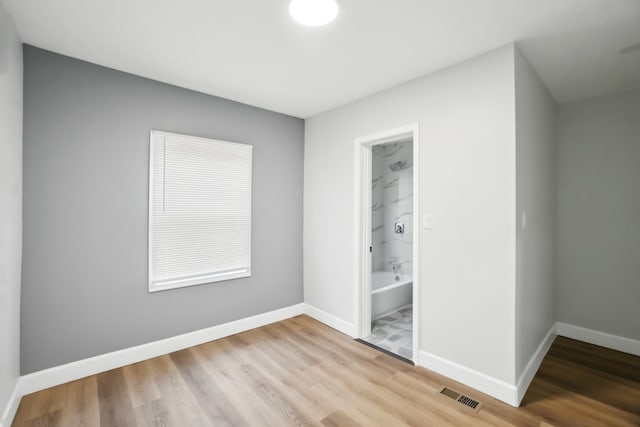 unfurnished bedroom featuring ensuite bathroom, light hardwood / wood-style floors, and a closet