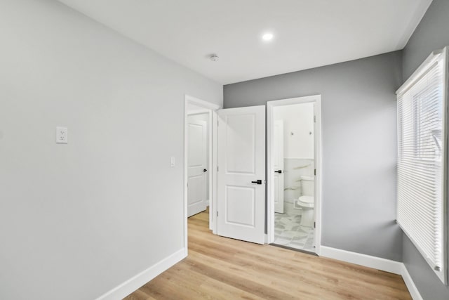 unfurnished bedroom featuring light hardwood / wood-style floors and ensuite bath