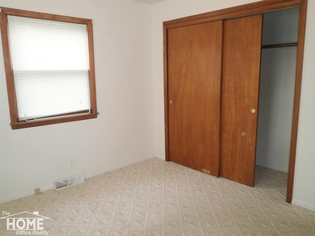 unfurnished bedroom featuring light carpet and a closet