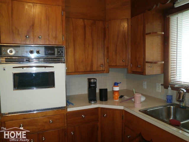 kitchen featuring oven, decorative backsplash, and sink