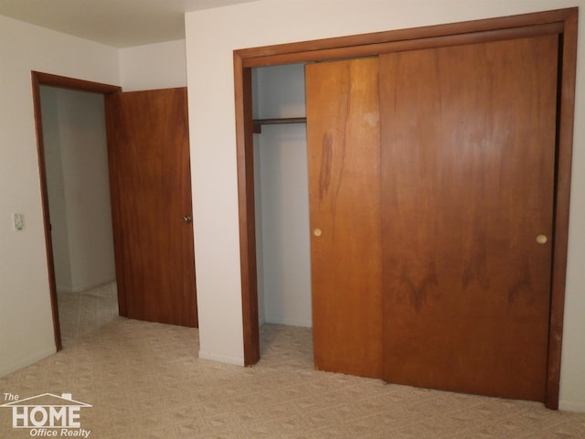 unfurnished bedroom featuring a closet and light colored carpet