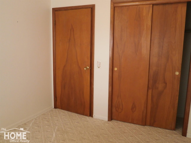 unfurnished bedroom featuring light carpet and a closet