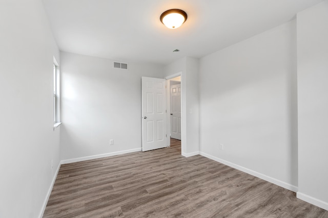 spare room featuring baseboards, visible vents, and wood finished floors