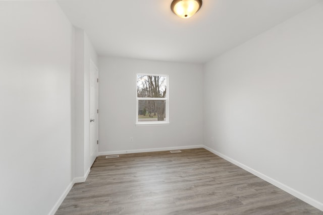 empty room featuring visible vents, baseboards, and wood finished floors