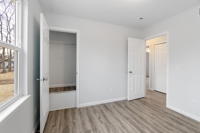 unfurnished bedroom with a closet, visible vents, light wood-style flooring, and baseboards