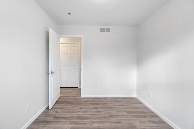 spare room featuring visible vents, baseboards, and wood finished floors