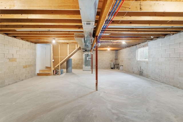 basement featuring stairway, visible vents, and heating unit