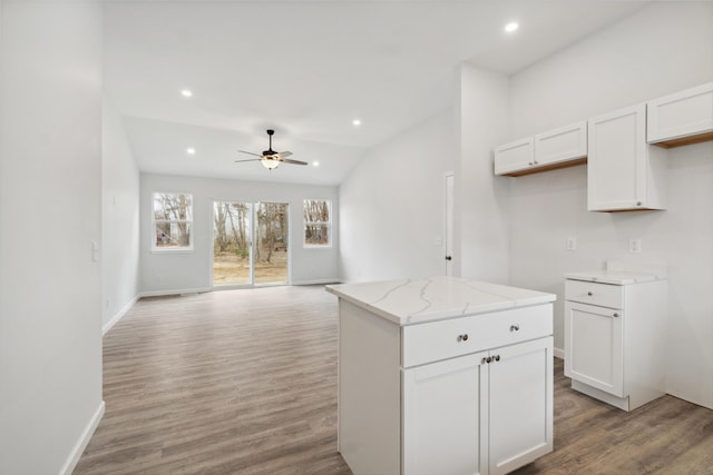 kitchen with light wood-type flooring, light stone countertops, white cabinetry, and recessed lighting