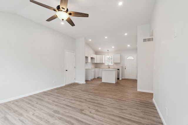 unfurnished living room featuring visible vents, baseboards, ceiling fan, light wood-style flooring, and vaulted ceiling