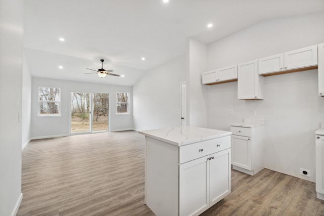 kitchen featuring light wood finished floors, light stone counters, a center island, white cabinetry, and recessed lighting